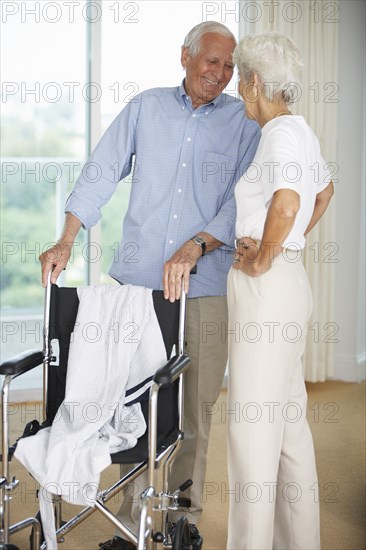 Senior couple standing by wheelchair
