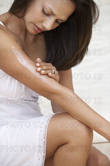 Indian woman applying moisturizer