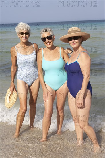 Senior women standing in waves on beach