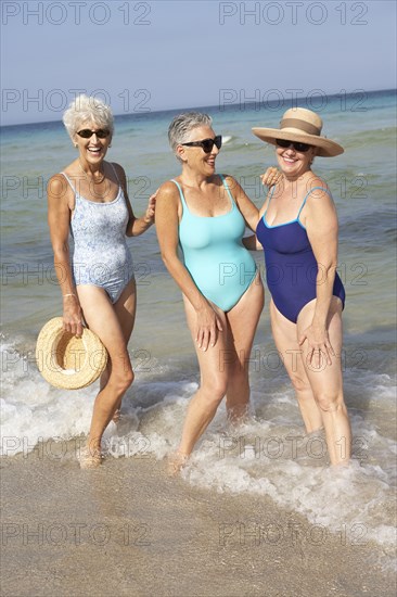 Senior women standing in waves on beach