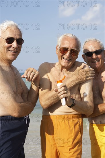 Senior men applying sunscreen on beach