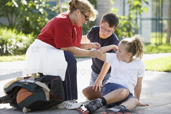 Mother bandaging daughter's scrape