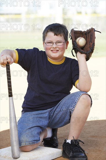 Boy holding baseball with mitt and bat