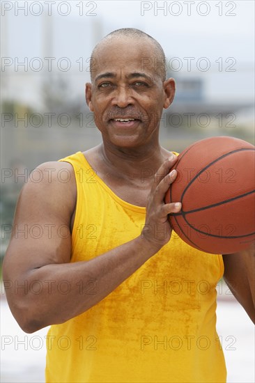 Senior man playing basketball outdoors