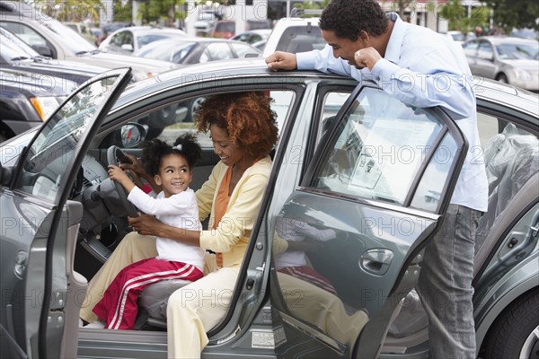 Black family admiring new car