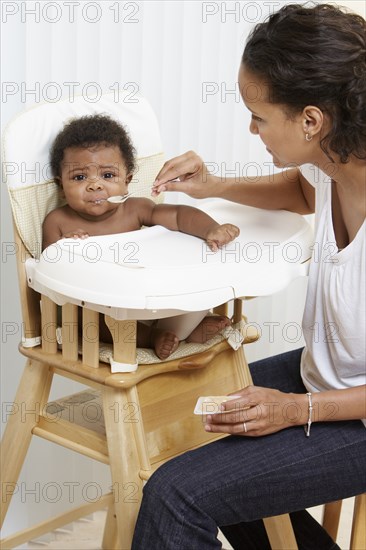 Mother feeding baby in high chair