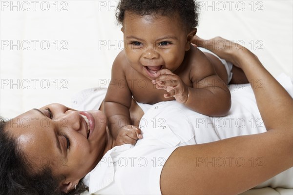 Mother and baby playing on bed