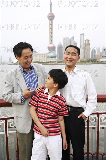 Three generations of men smiling by city skyline