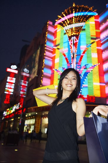 Smiling woman on city street lit up at night