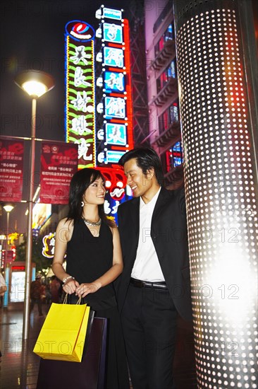 Couple on city street lit up at night