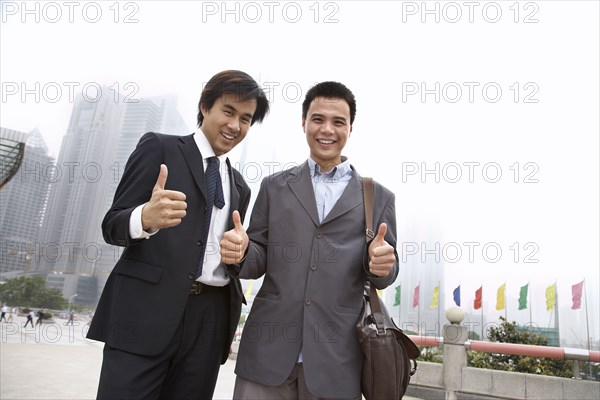 Chinese businessmen giving 'thumbs up' on city street