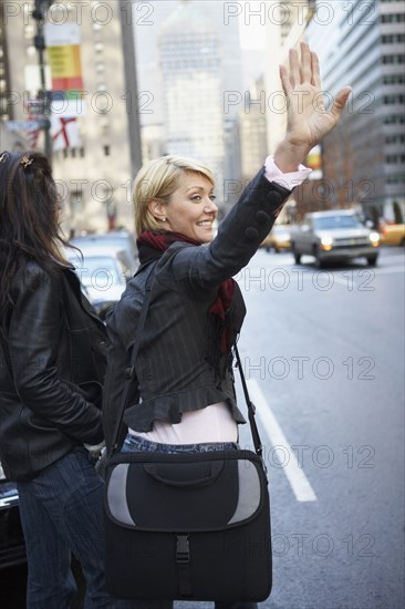 Women hailing taxi on city street