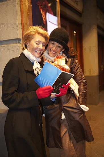 Caucasian women reading on city street at night