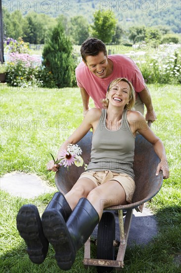 Man pushing girlfriend in wheelbarrow