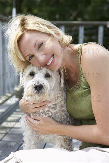 Woman petting dog on wooden patio