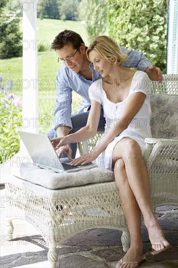 Couple using laptop together on patio