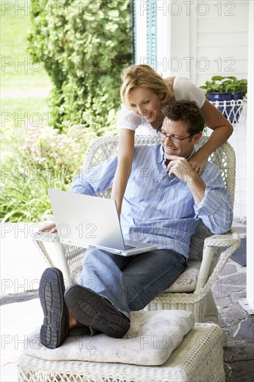 Couple using laptop together on patio