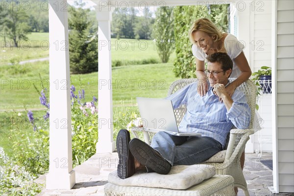 Couple using laptop together on patio