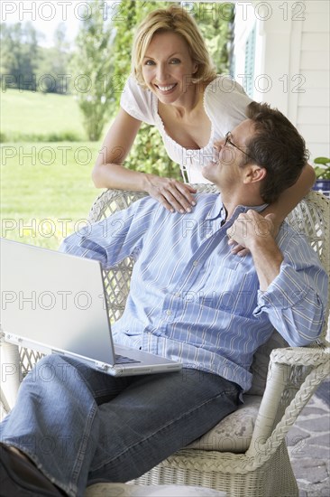 Couple using laptop together on patio