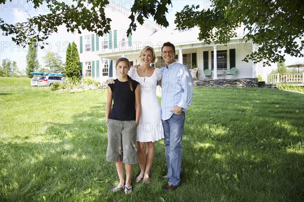 Family standing outside suburban house