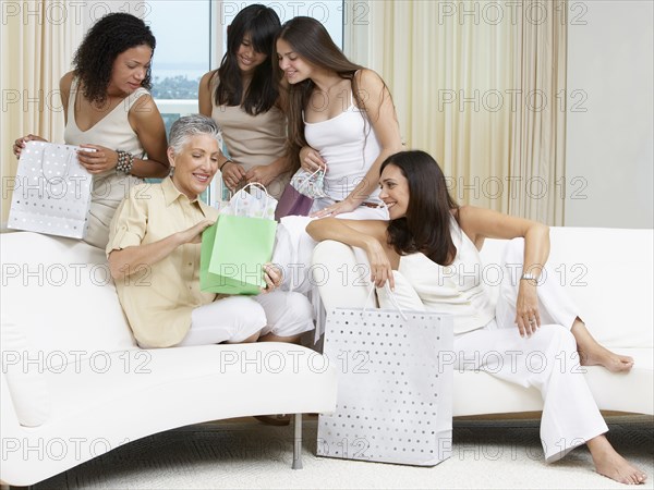 Woman opening presents with friends on sofa