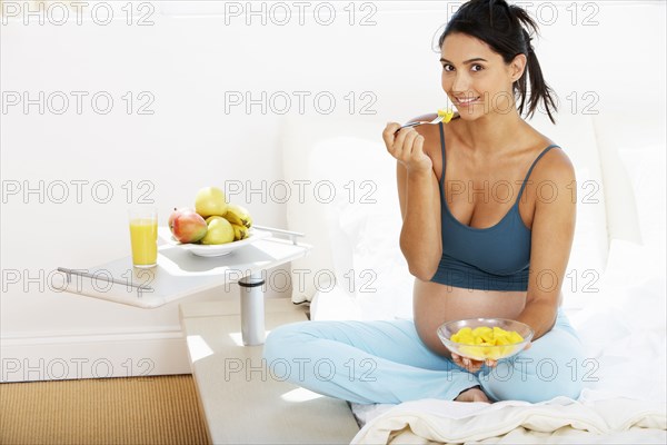 Pregnant Hispanic woman eating fruit