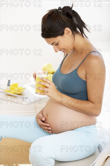 Pregnant Hispanic woman drinking fruit juice