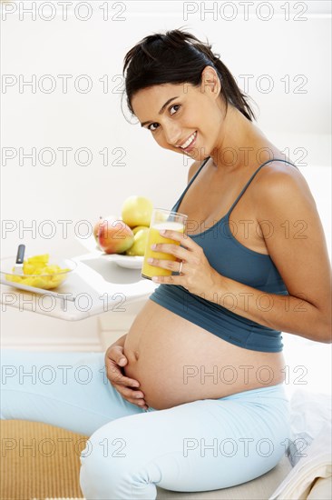 Pregnant Hispanic woman drinking fruit juice