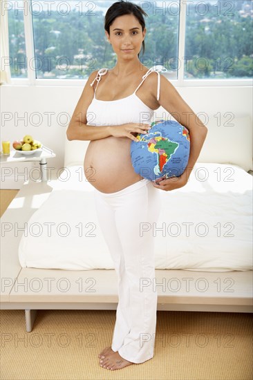 Pregnant Hispanic woman holding globe