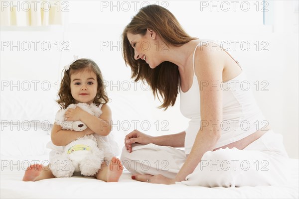 Caucasian mother and daughter playing with teddy bear