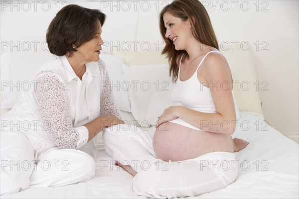Mother examining daughter's pregnant belly