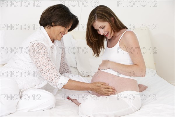Mother rubbing daughter's pregnant belly