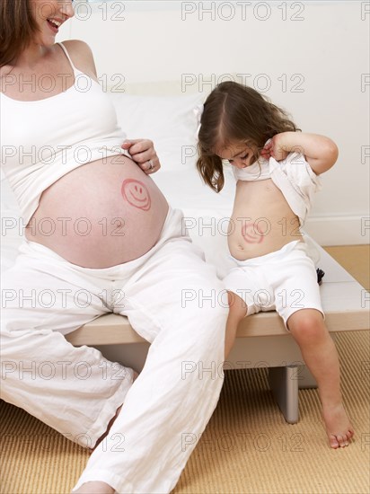 Caucasian girl and pregnant mother with drawings on bellies