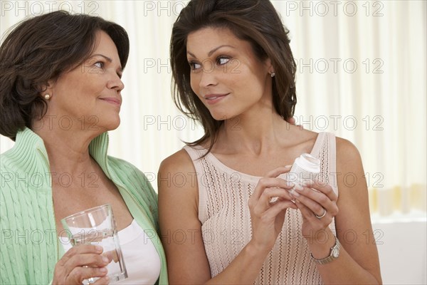 Hispanic woman giving mother medicine