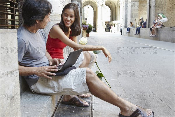 Couple using laptop on city street