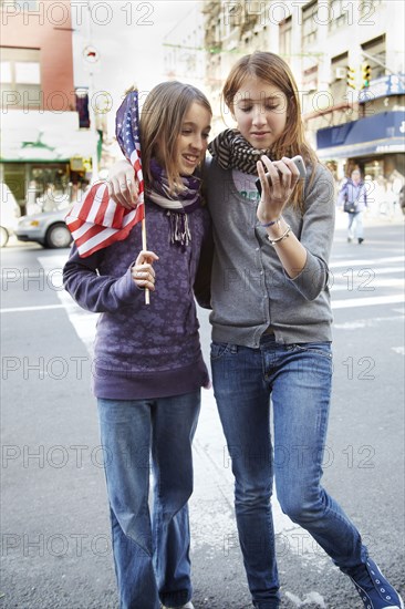 Girls checking cell phone on city street