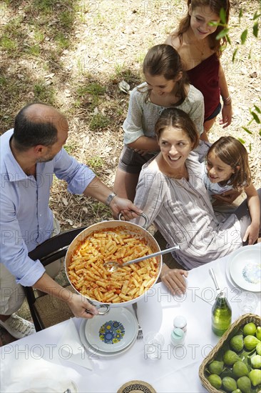 Family eating together at table outdoors