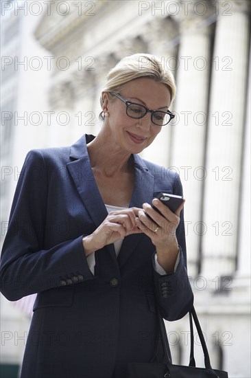 Caucasian businesswoman using cell phone in city street