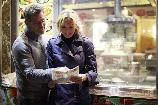 Caucasian couple reading menu at food cart