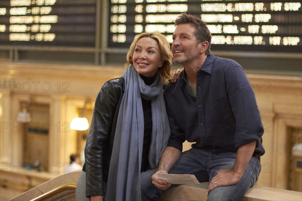 Caucasian couple reading train schedule in Grand Central Station