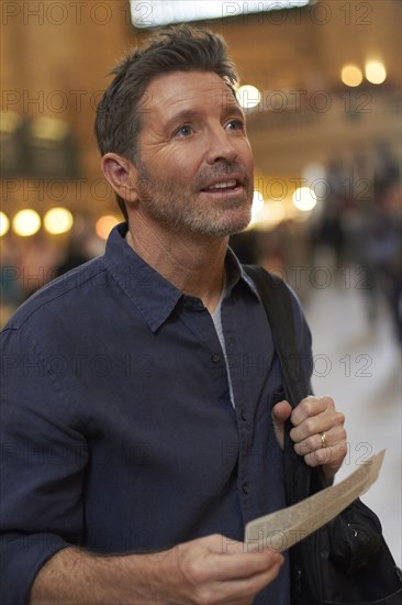 Caucasian man reading train schedule in Grand Central Station