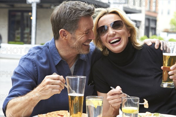 Caucasian couple drinking and eating at sidewalk cafe