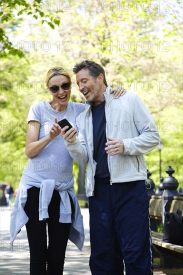 Caucasian couple using cell phone in park