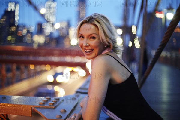 Caucasian woman leaning on railing on Brooklyn Bridge