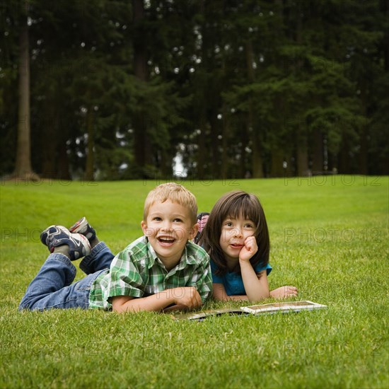 Brother and sister reading story book in park