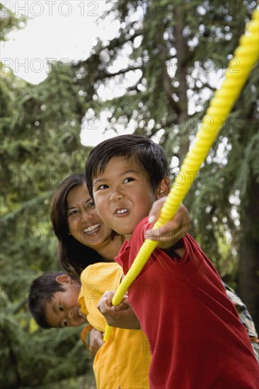 Asian mother and sons playing tug-of-war