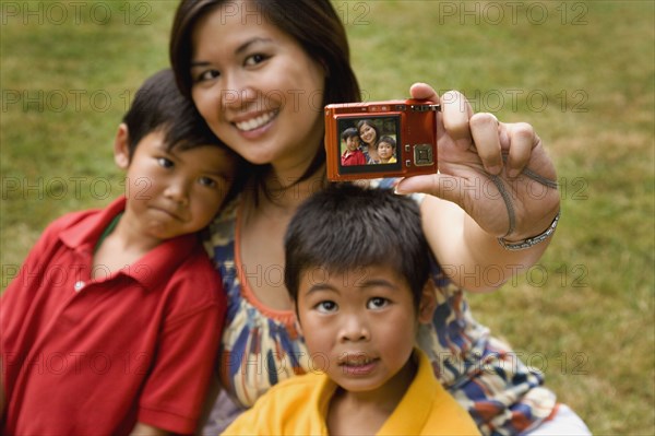 Asian mother and sons taking self-portrait