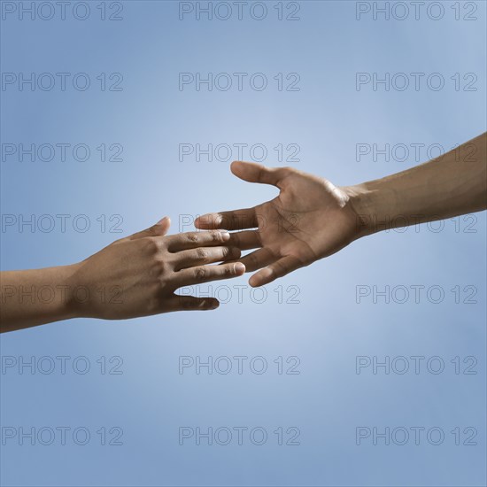 Mixed race people reaching out hands toward one another