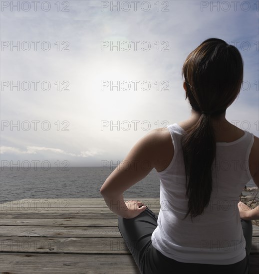 Filipino woman sitting on dock near ocean