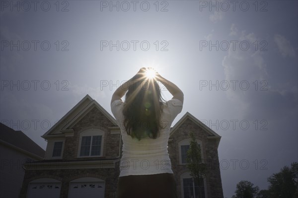 Chinese woman with arms raised looking at sun